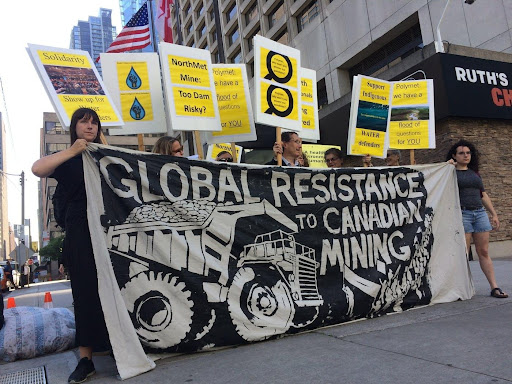 a group of people protesting and holding a banner against mining