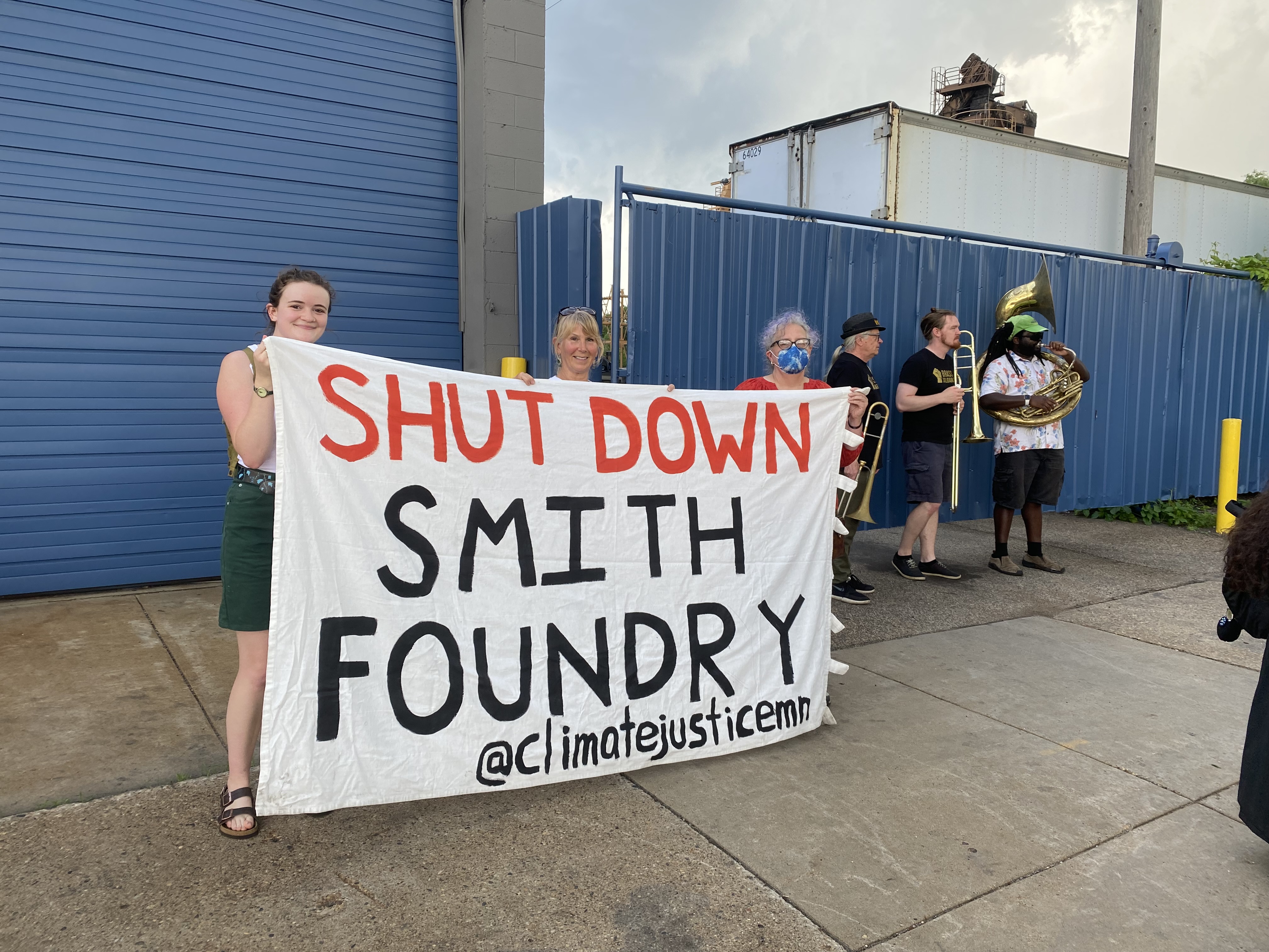 three white women hold sign that says shut down smith foundry