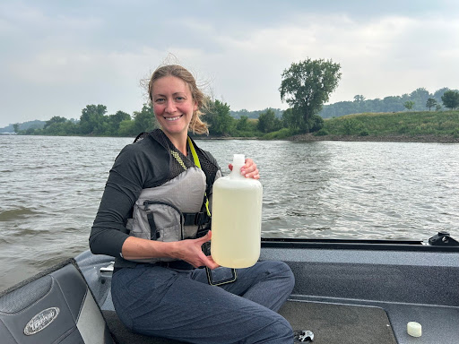 a smiling white holding a water sample