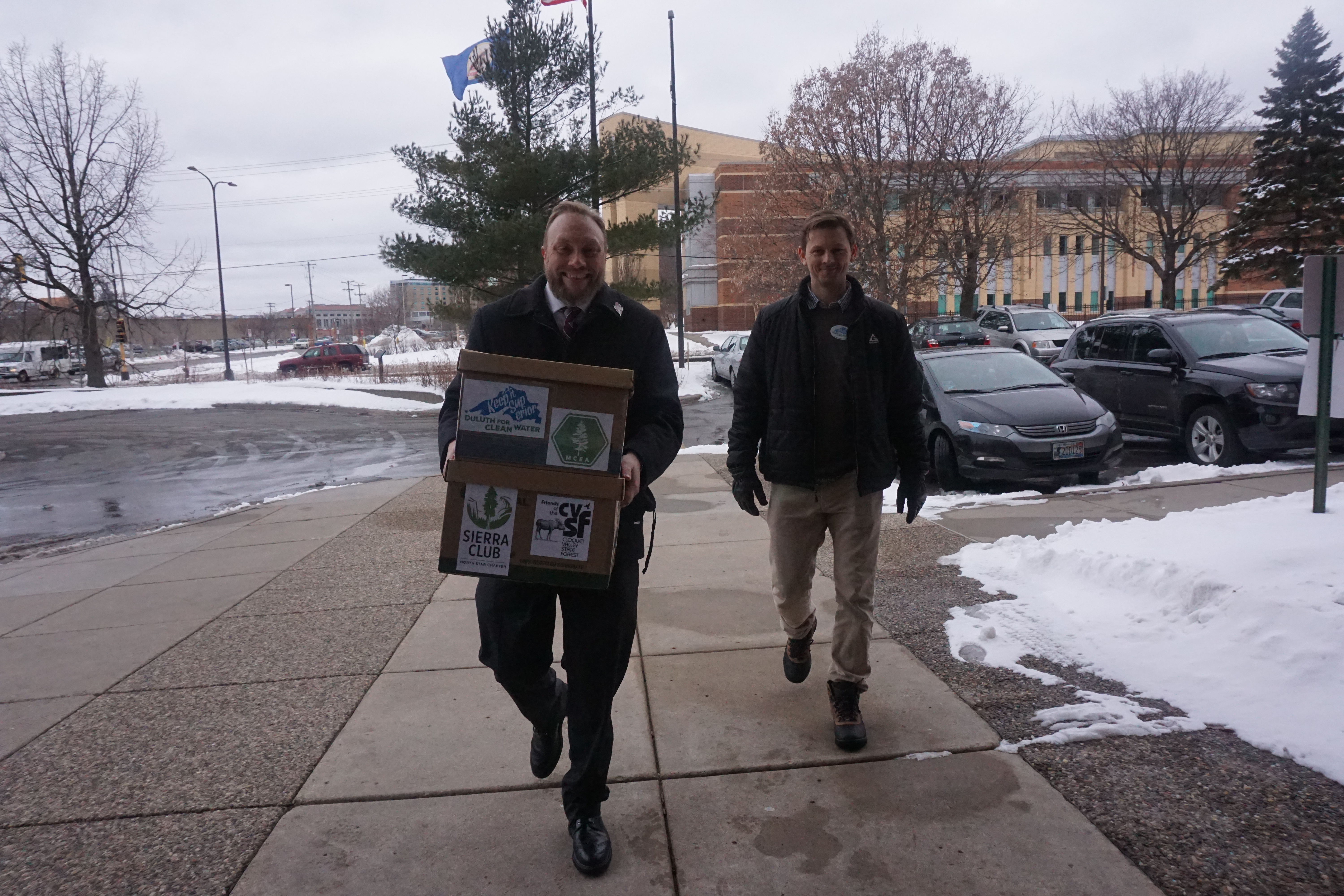 two white men carry boxes of comments