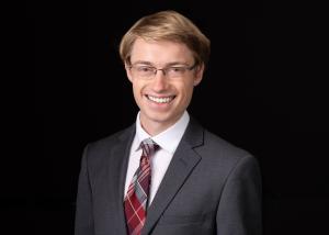 a white man in a red tie against a dark background