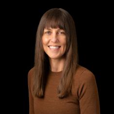 photo of a white woman smiling with brown hair in a brown shirt