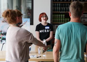 photo of a red haired white woman laughing with supporters wearing an M C E A t-shirt