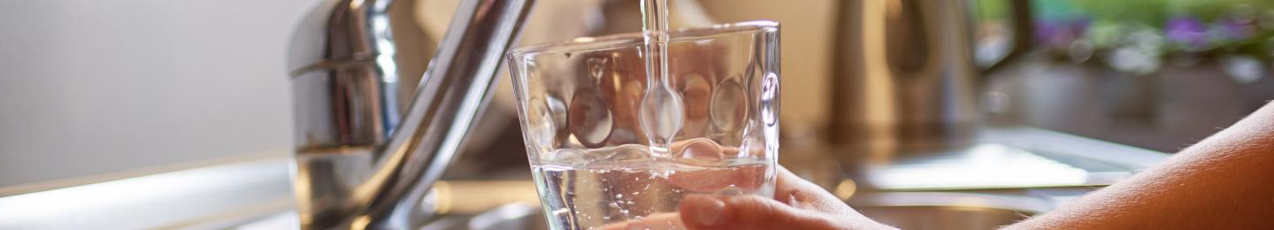 image of person filling water glass at a sink