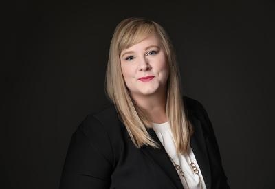 a white woman with straight hair sitting in front of a dark background