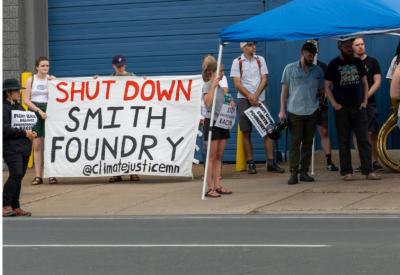 a crowd standing with a sign that says shut down smith foundry