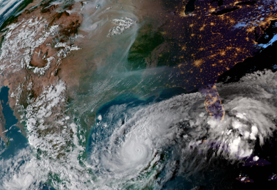 A satellite view of North America on October 7, 2024, showing wildfire smoke from the west snaking across the middle of the continent, and a Category 5 Hurricane Milton churning in the Gulf of Mexico.